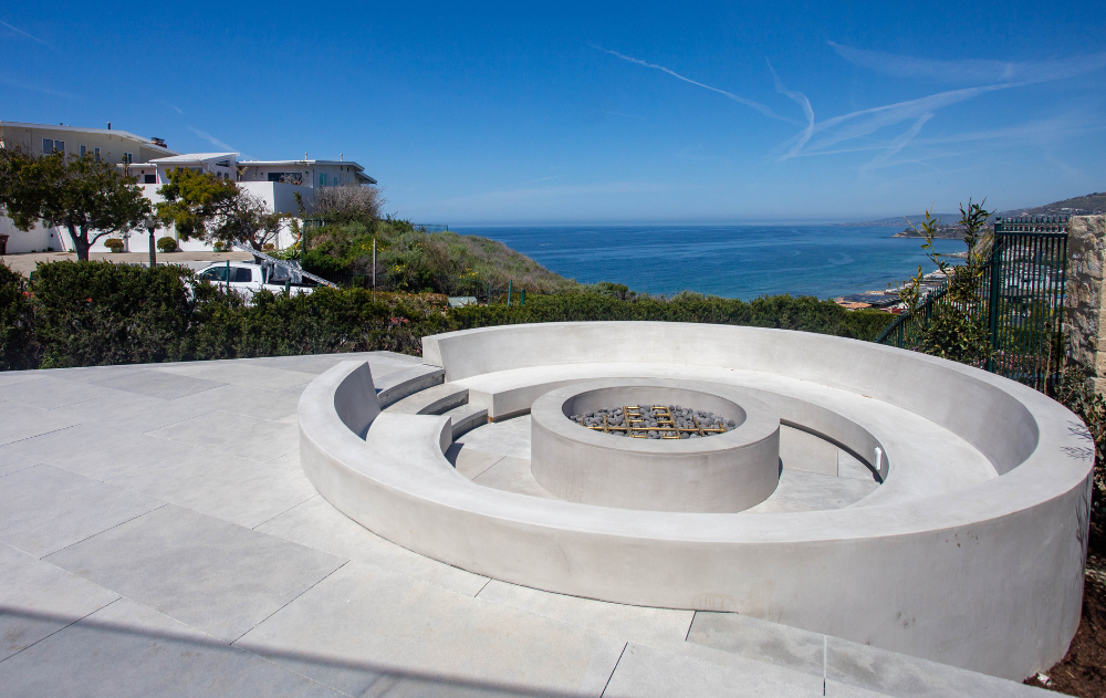 Outdoor fireplace feature with large-format porcelain patio overlooking the Pacific Ocean