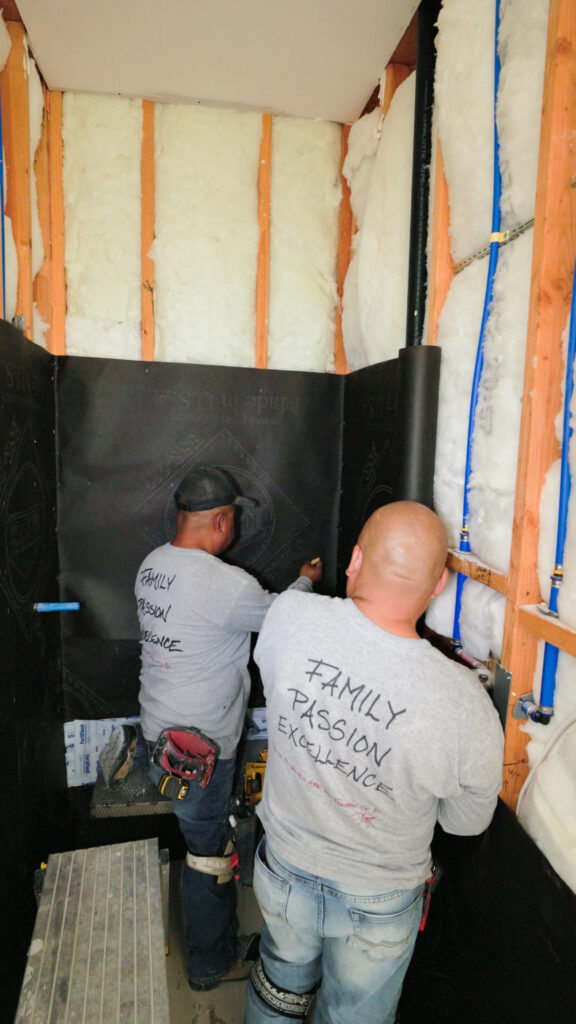 Waterproofing membrane installed on a shower substrate before natural stone installation.